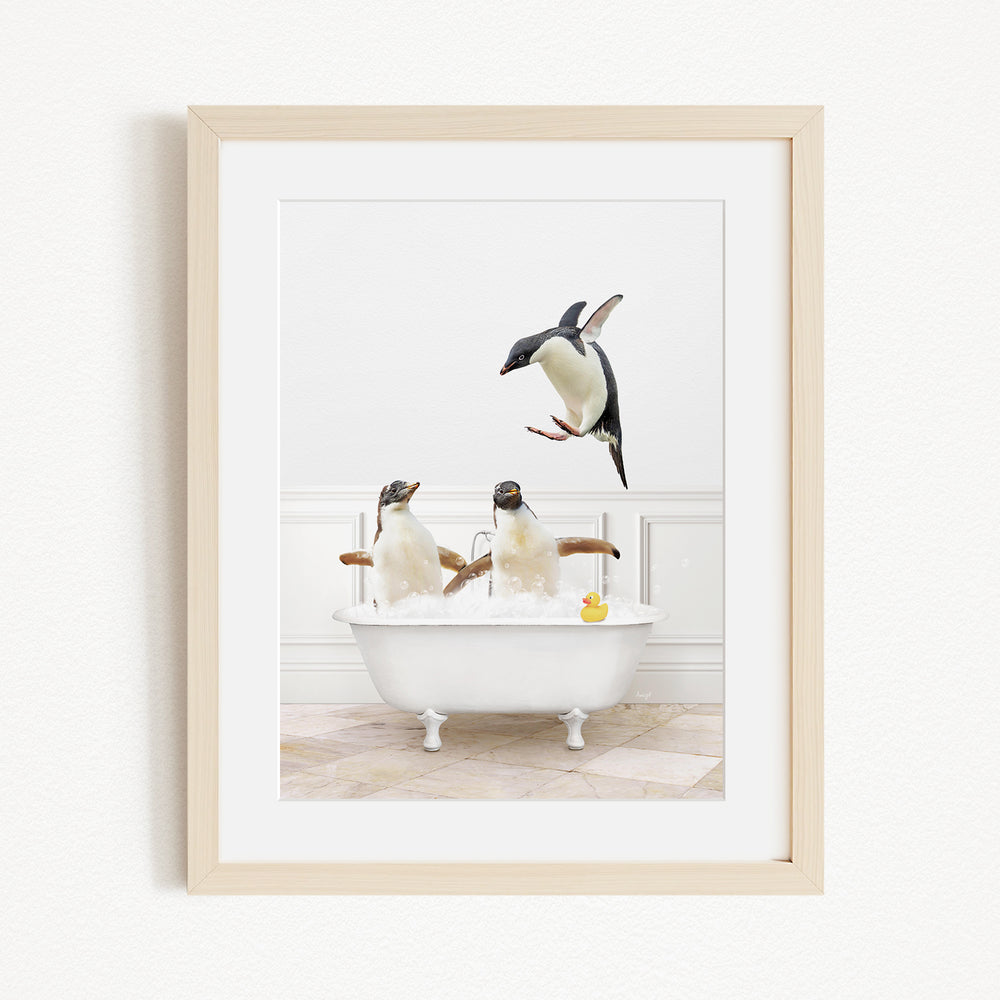A framed image depicting three penguins sitting in a bathtub, with one penguin flying towards the tub.