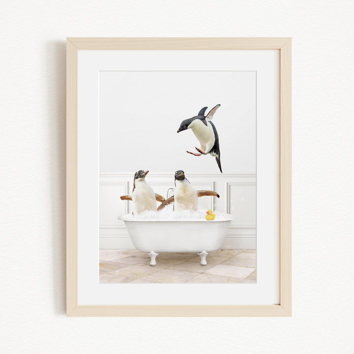 A framed image depicting three penguins sitting in a bathtub, with one penguin flying towards the tub.