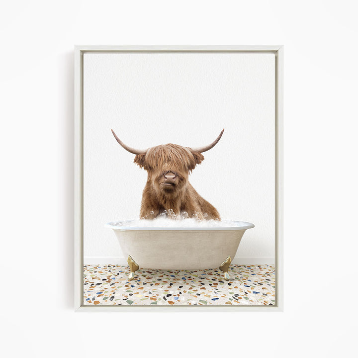 A brown cow with long horns is sitting in a white bathtub filled with water, creating a whimsical and playful scene.