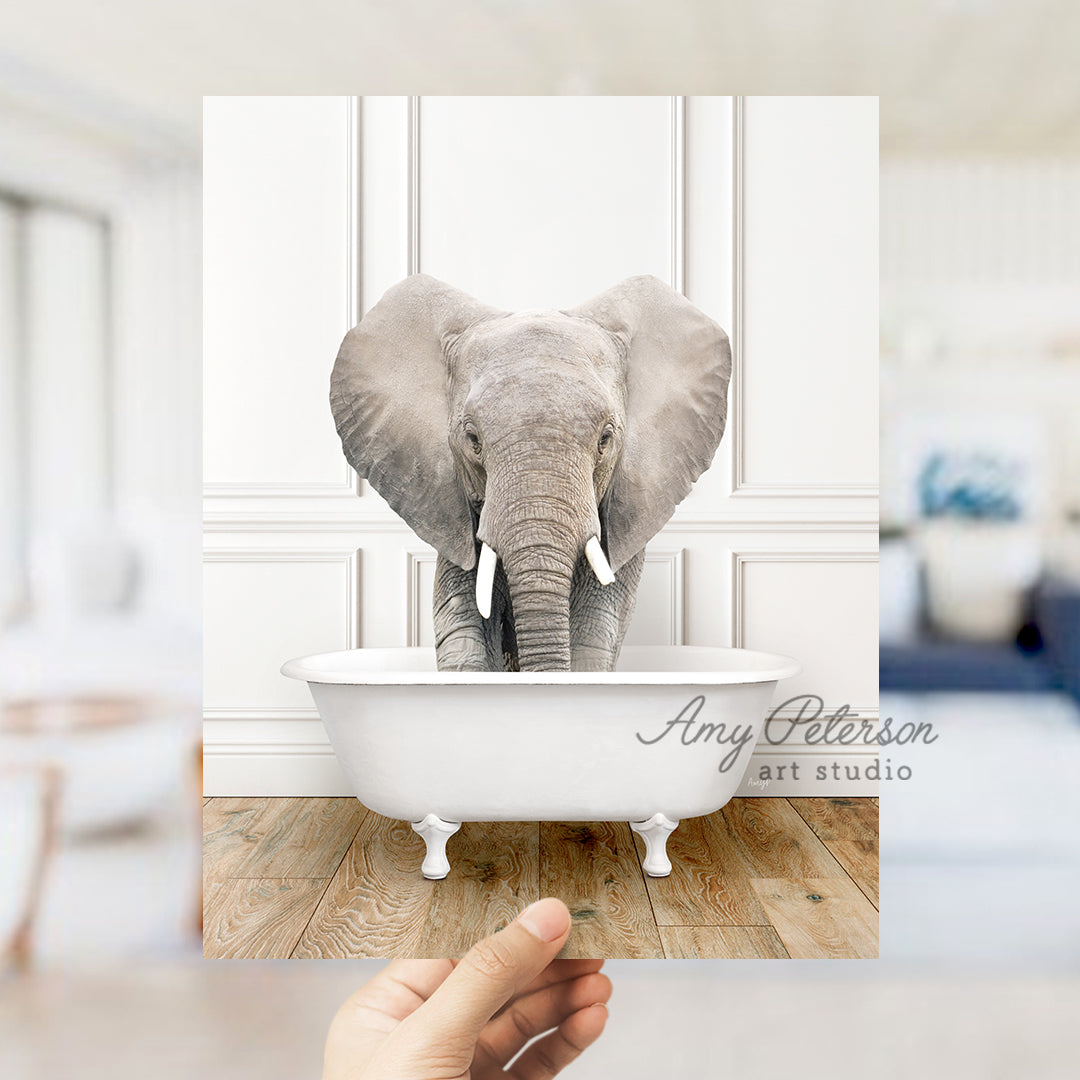 a hand holding a photo of an elephant in a bathtub