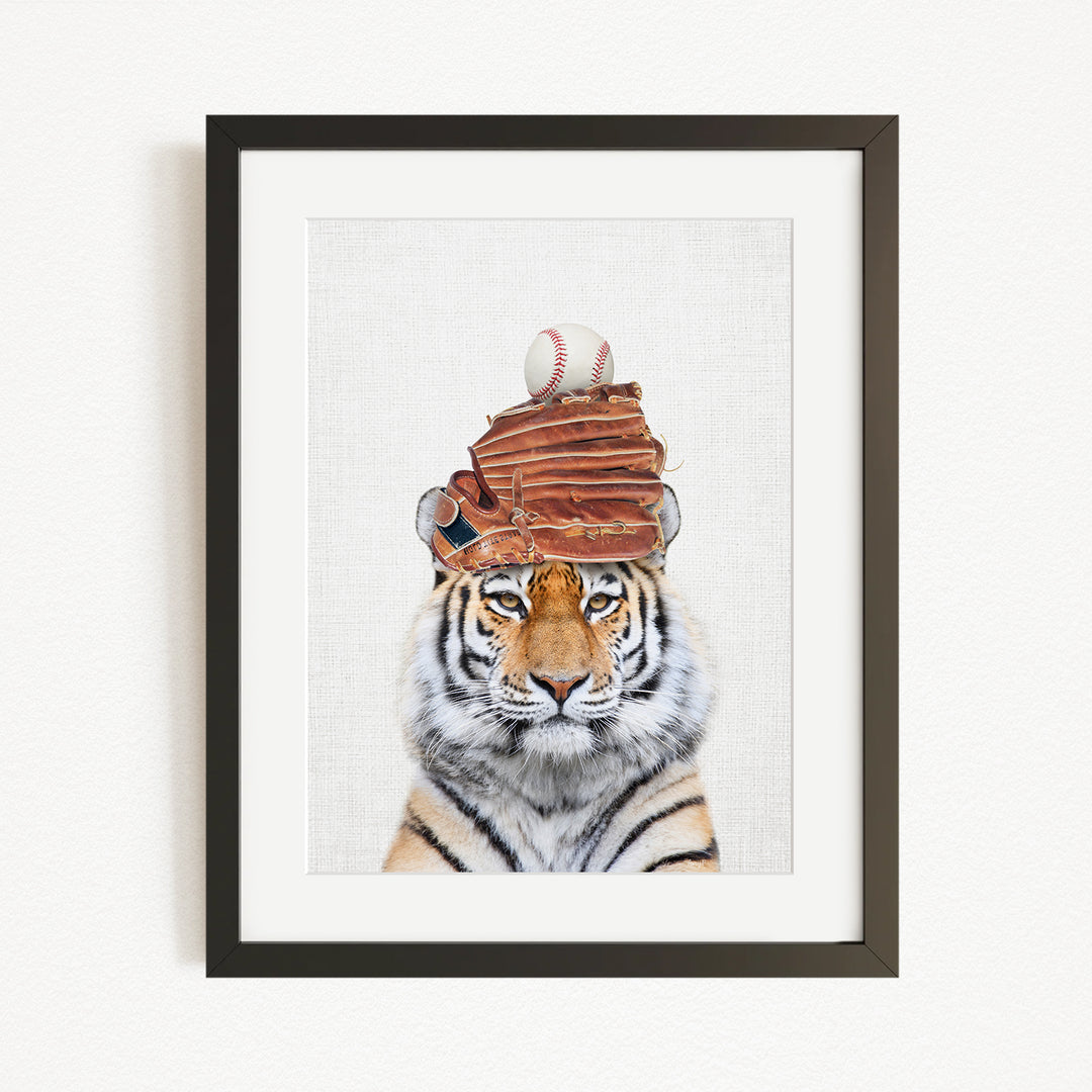 A tiger wearing a baseball cap and holding a baseball in its mouth, with a stack of baseball gloves on its head.