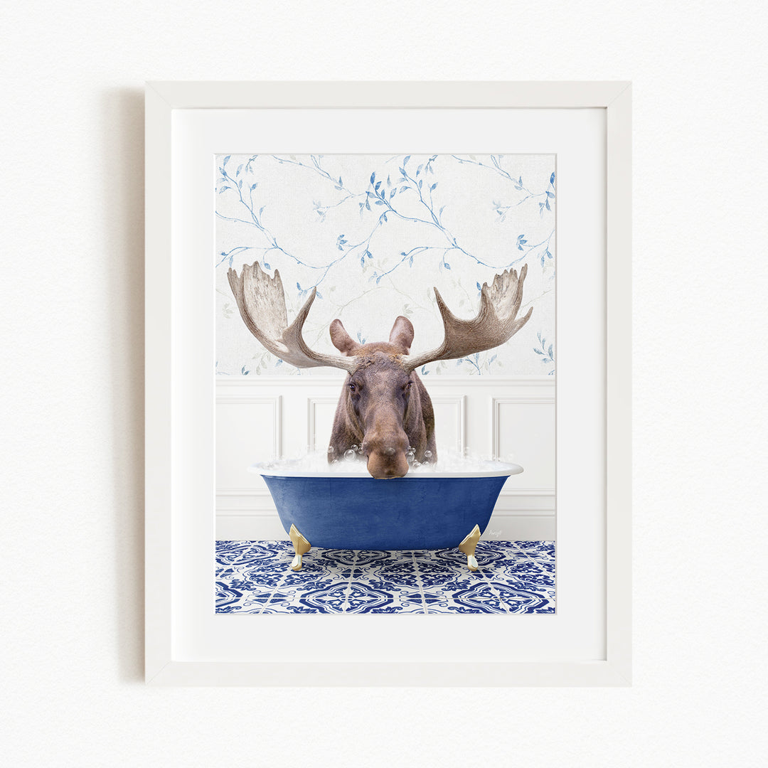 A moose with large antlers is sitting in a blue bathtub, surrounded by a blue and white patterned rug and a floral wallpaper background.