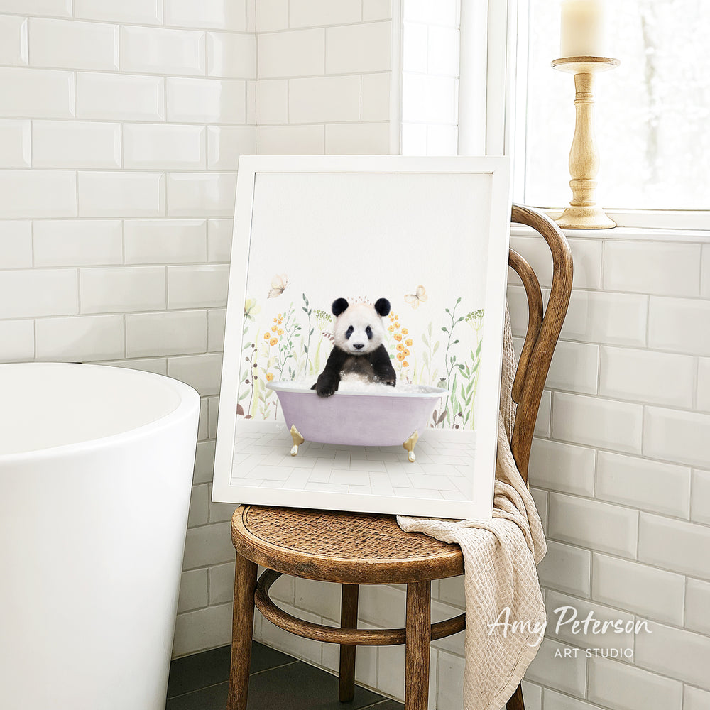 A framed illustration of a panda sitting in a bathtub is displayed on a wooden chair in a bathroom setting.