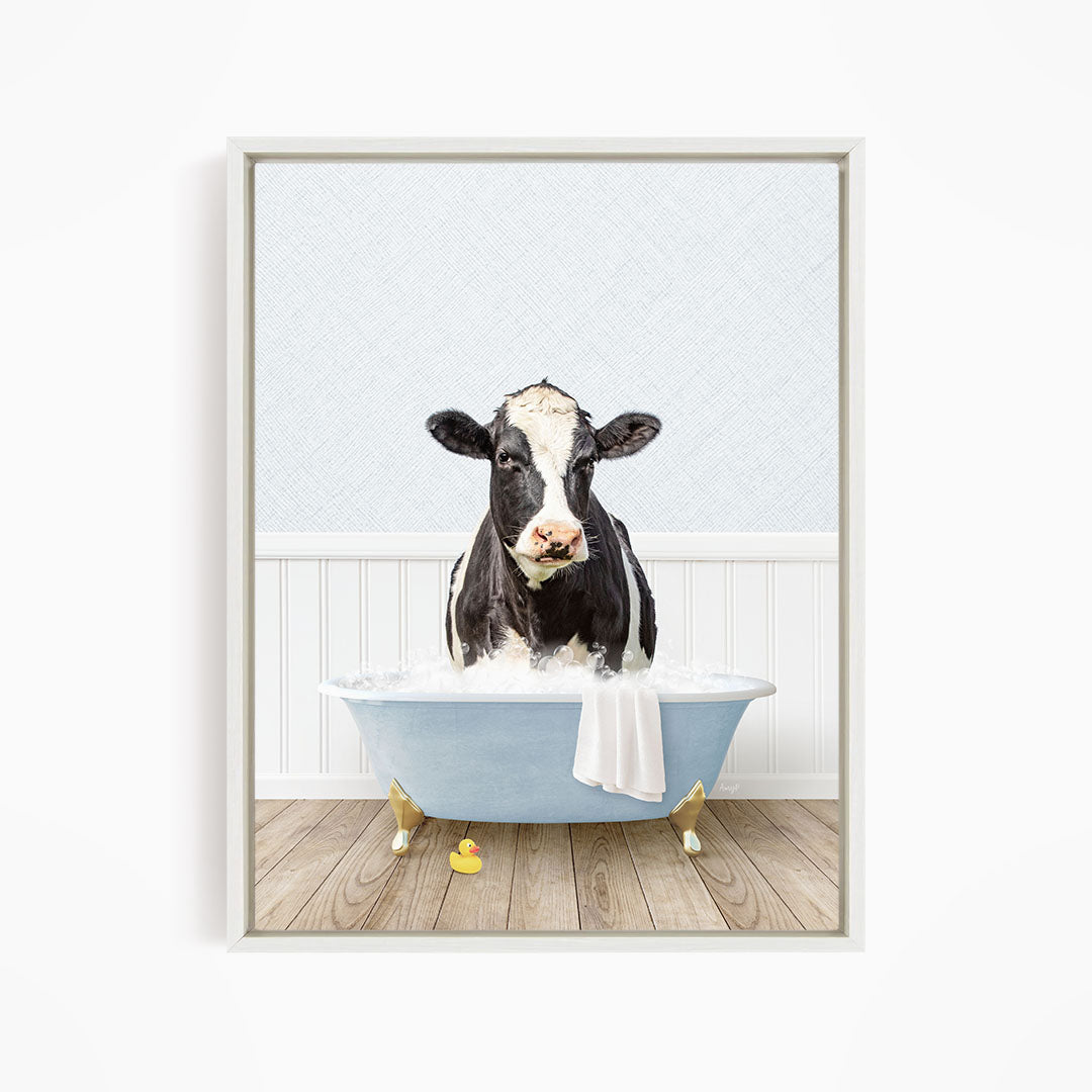 A black and white cow is sitting in a blue bathtub filled with water, surrounded by rubber duckies.