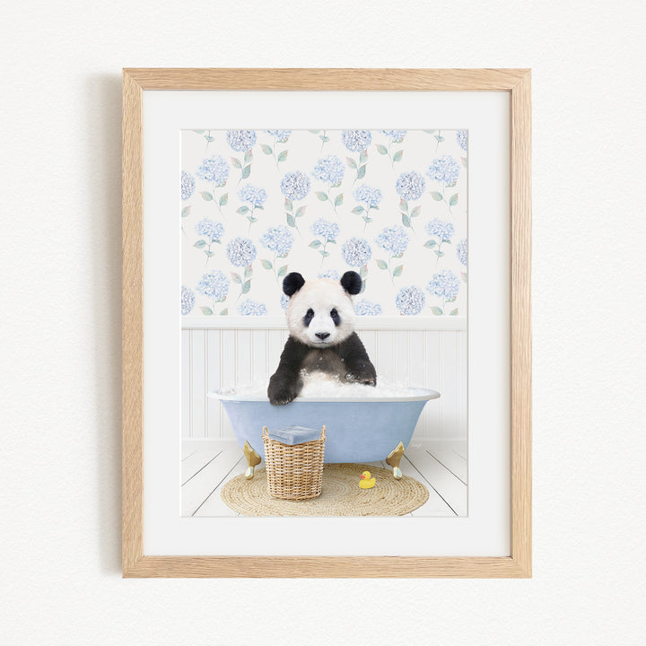 A panda bear sitting in a blue bathtub filled with bubbles, surrounded by a floral patterned wall and a basket of rubber ducks.