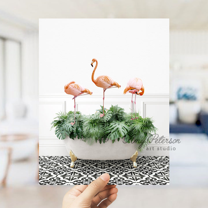 a hand holding a card with three flamingos in a bathtub