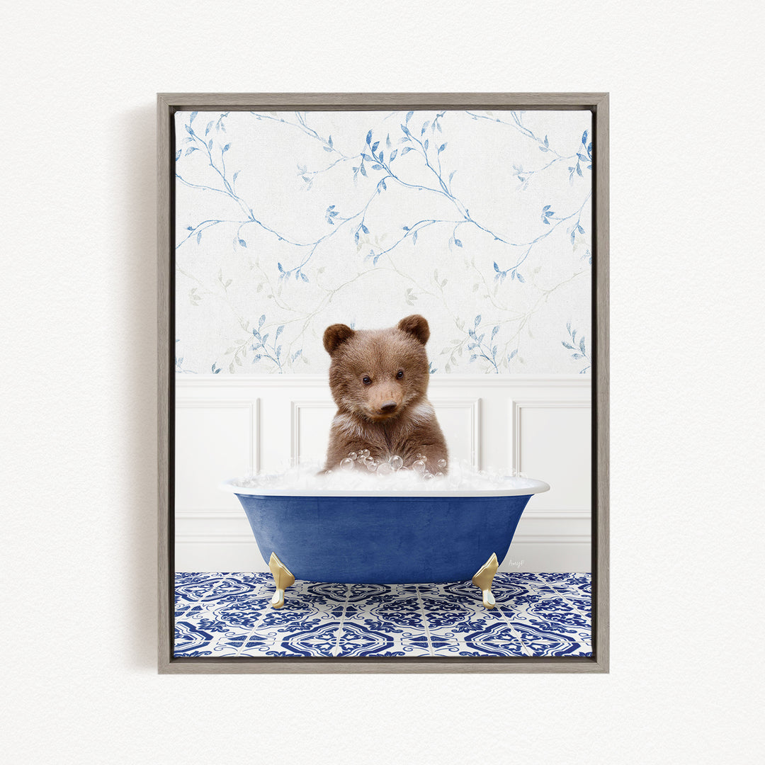 A brown bear sitting in a blue bathtub filled with bubbles, surrounded by a blue and white patterned rug and a floral wallpaper.