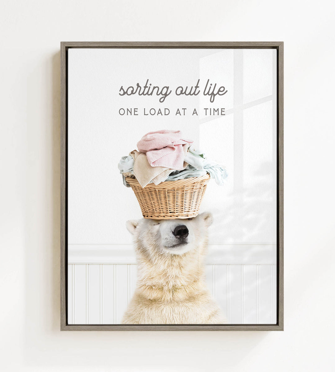A polar bear balancing a basket of laundry on its head, with the text "sorting out life" and "ONE LOAD AT A TIME" displayed above the image.