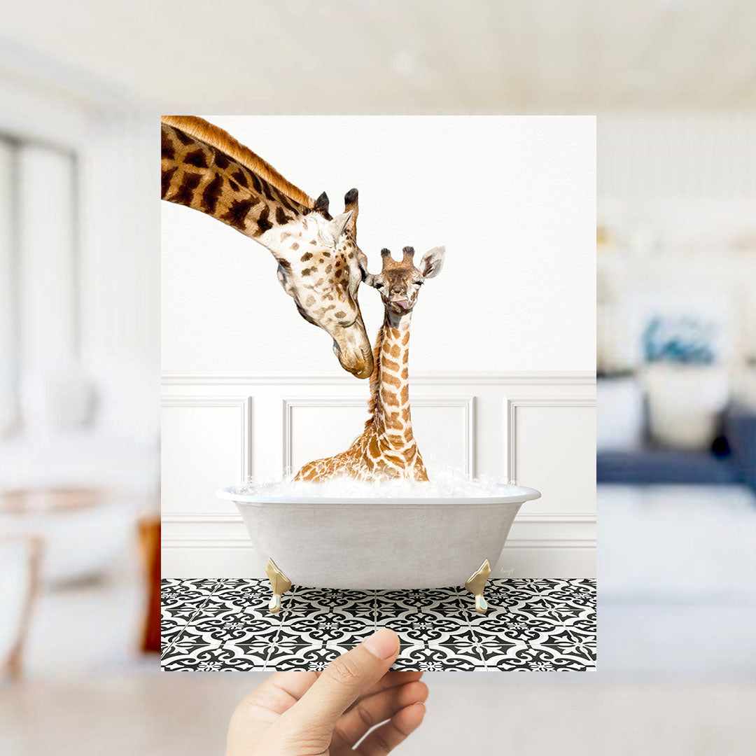 A mother giraffe and her baby giraffe are sitting together in a white bathtub, with the mother gently licking her baby.