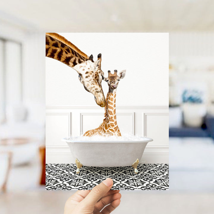 A mother giraffe and her baby giraffe are sitting together in a white bathtub, with the mother gently licking her baby.