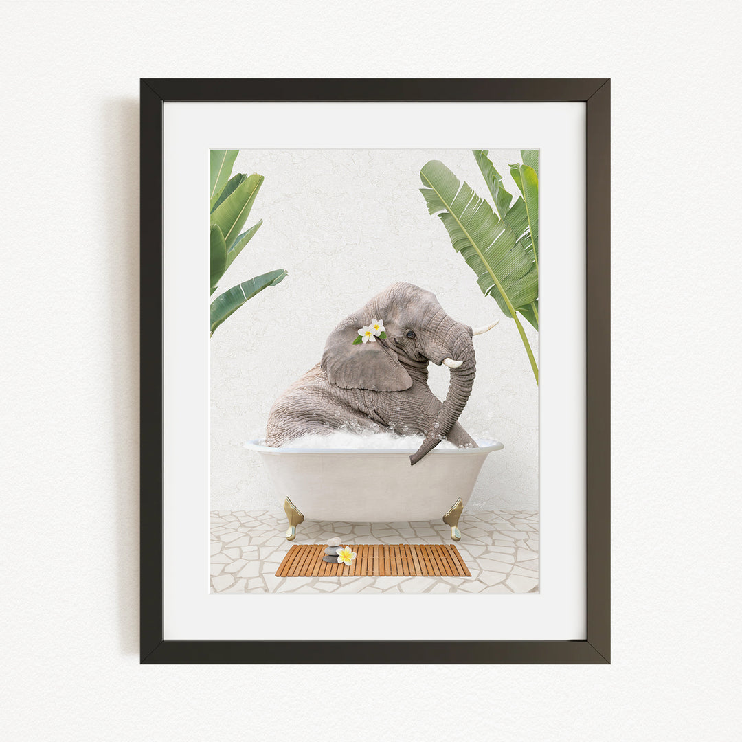 A gray elephant is sitting in a white bathtub, surrounded by green leaves and a wooden mat, creating a whimsical and relaxing scene.