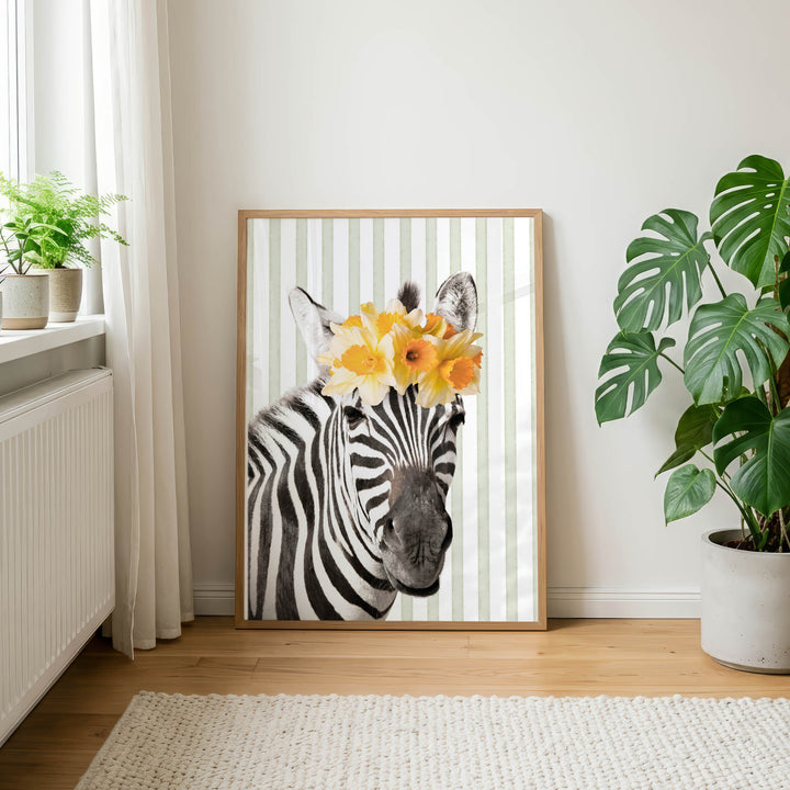 A framed photograph of a zebra wearing a yellow flower crown is displayed on a wall in a room with a rug and potted plants.