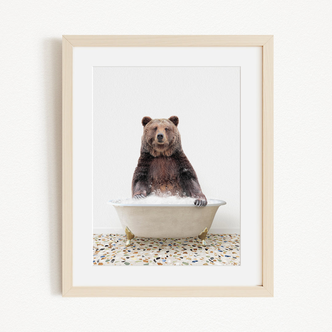 A brown bear sitting in a white bathtub filled with water, with a speckled floor beneath it.