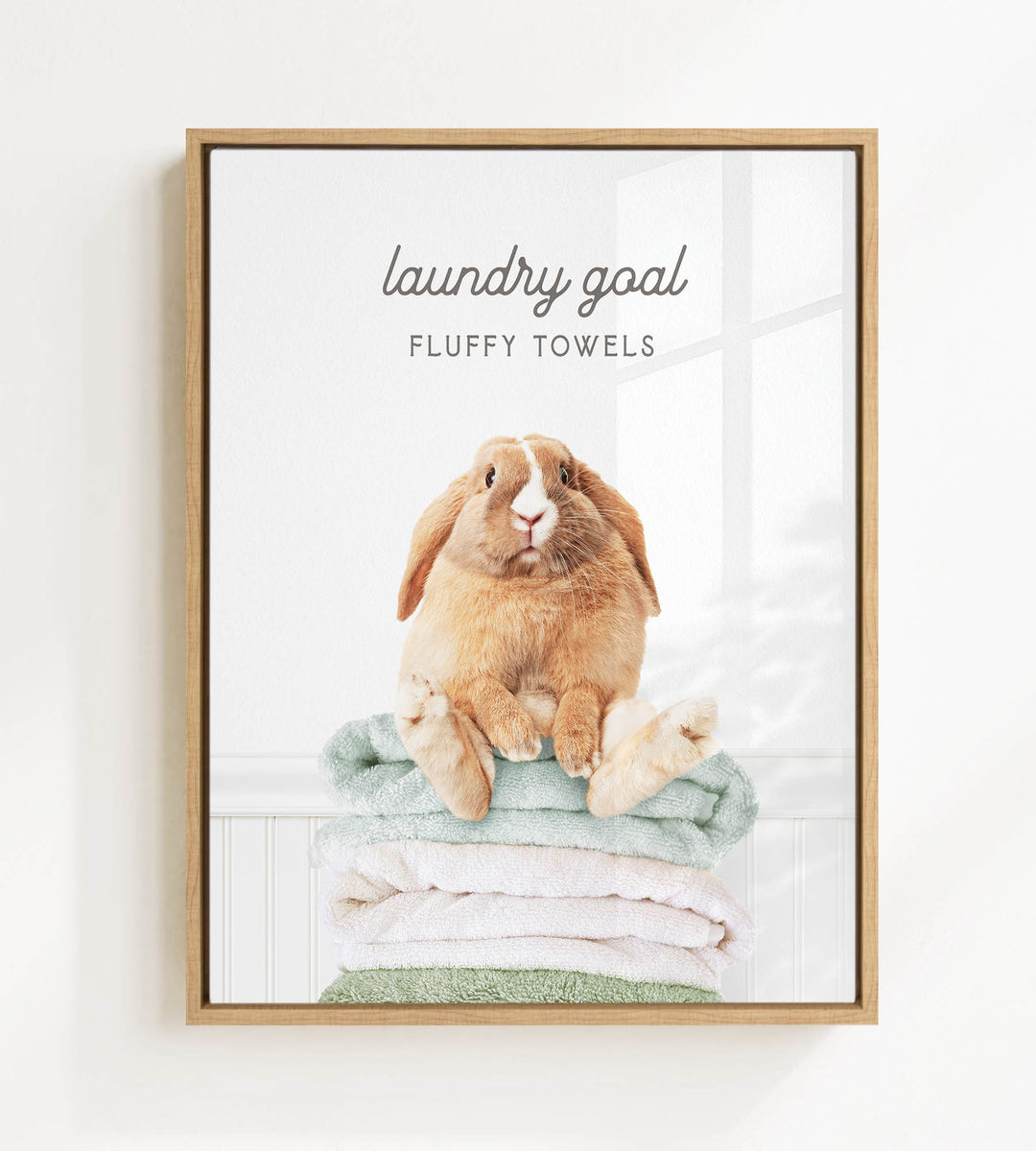 A fluffy rabbit sitting on a stack of towels, with the text "laundry goal" and "FLUFFY TOWELS" displayed above the image.