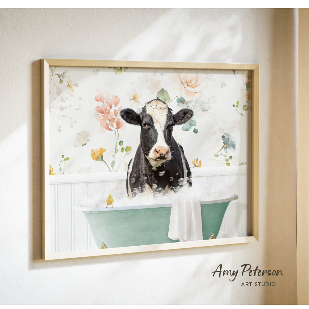 A framed print of a black and white cow sitting in a green bathtub filled with bubbles, surrounded by a floral pattern.