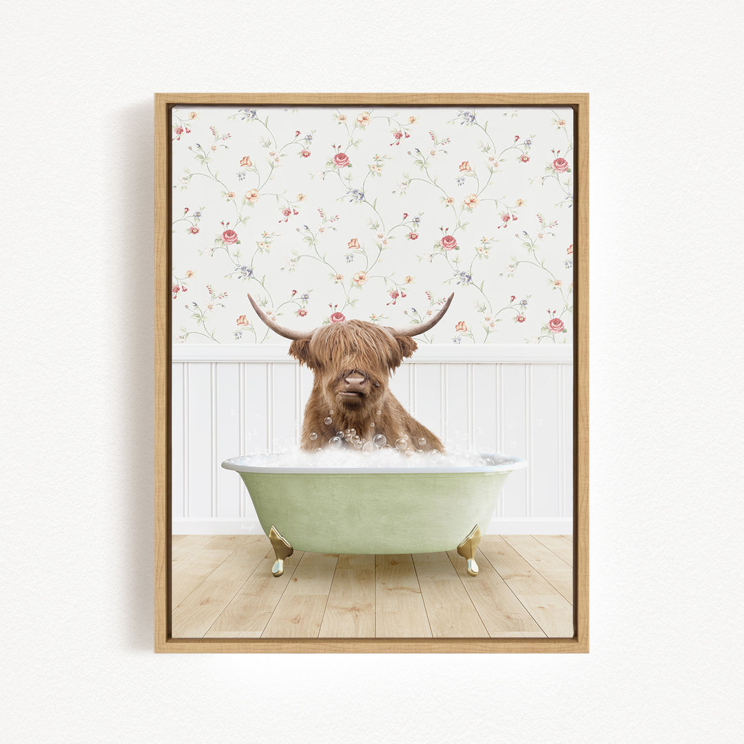 A brown cow with long horns is sitting in a green bathtub filled with bubbles, against a floral wallpaper background.