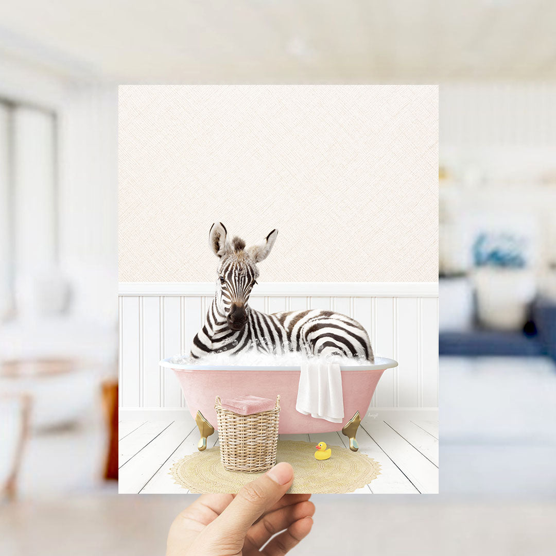 A zebra is sitting in a pink bathtub filled with water, surrounded by a yellow rubber duck and a white towel.