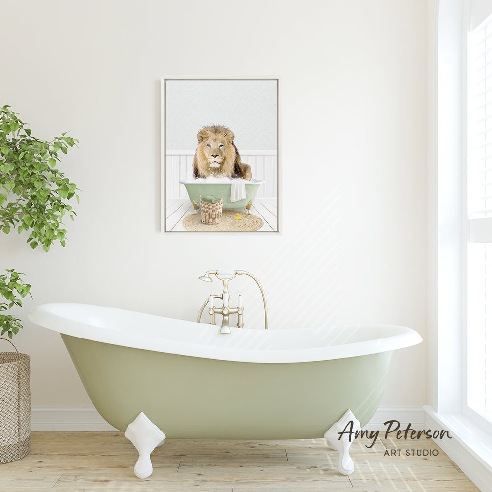 A framed image of a lion sitting in a bathtub is displayed on the wall above a green clawfoot bathtub in a bathroom.