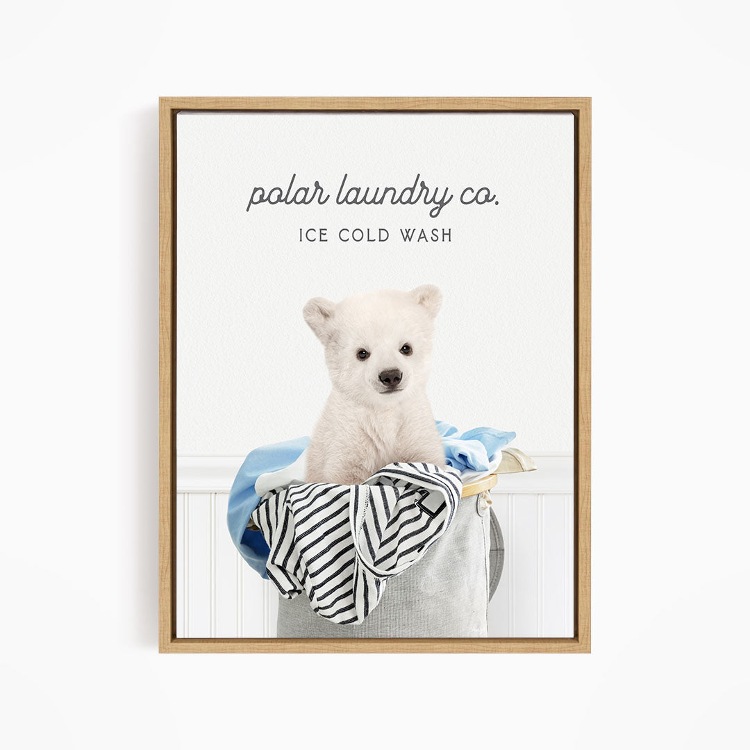 A white polar bear sitting in a laundry basket filled with clothes, with the text "polar laundry co. ICE COLD WASH" displayed above the image.