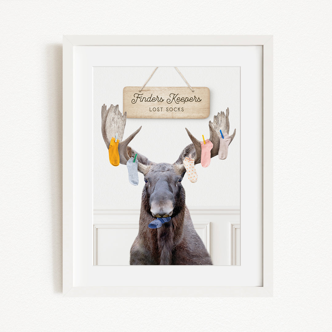 A framed image of a moose with a sign above it that says "Finders Keepers Lost Socks".