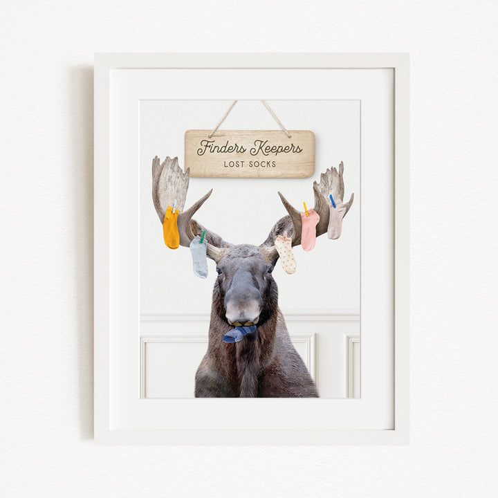 A framed image of a moose with a sign above it that says "Finders Keepers Lost Socks".