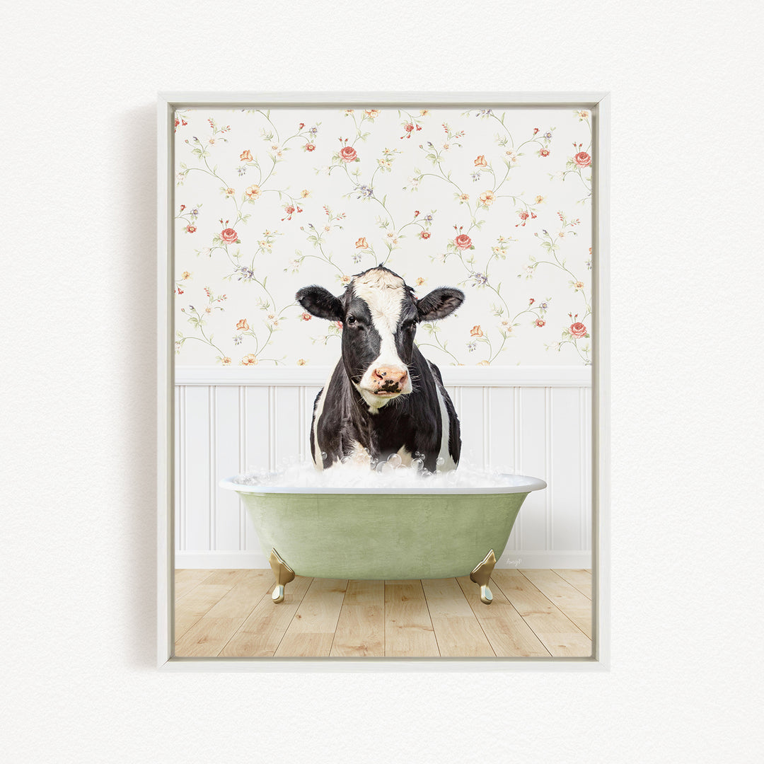 A black and white cow is sitting in a green bathtub filled with water, with a floral wallpaper in the background.