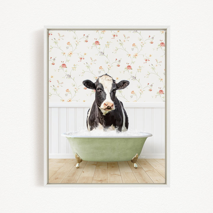 A black and white cow is sitting in a green bathtub filled with water, with a floral wallpaper in the background.