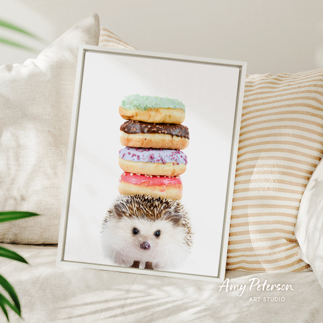 A framed image of a hedgehog sitting on top of a stack of colorful donuts.