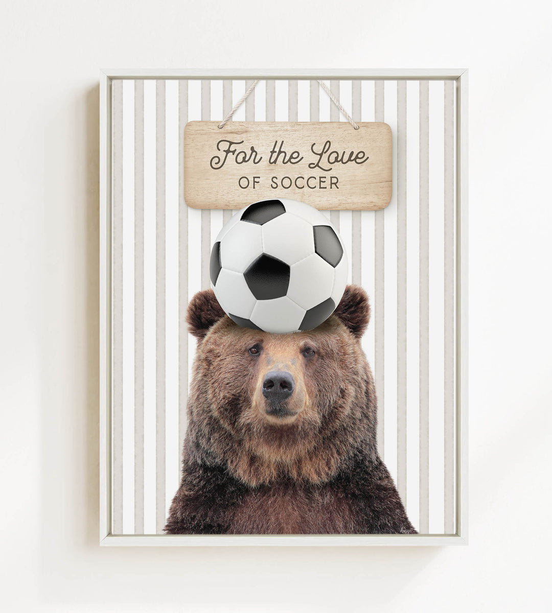 A brown bear with a soccer ball on its head, with a wooden sign above that says "For the Love of Soccer".