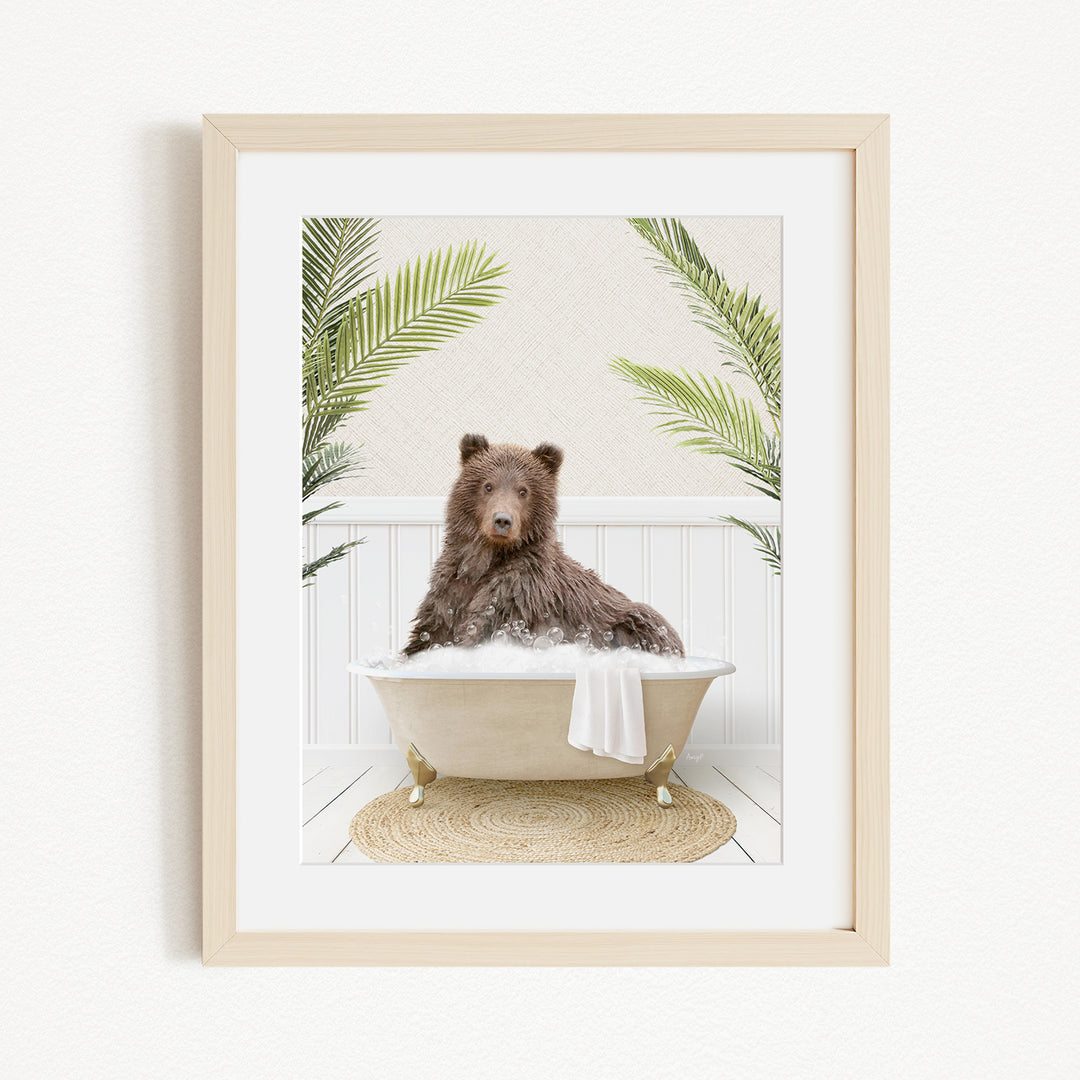 A brown bear sitting in a bathtub filled with bubbles, surrounded by green palm leaves.