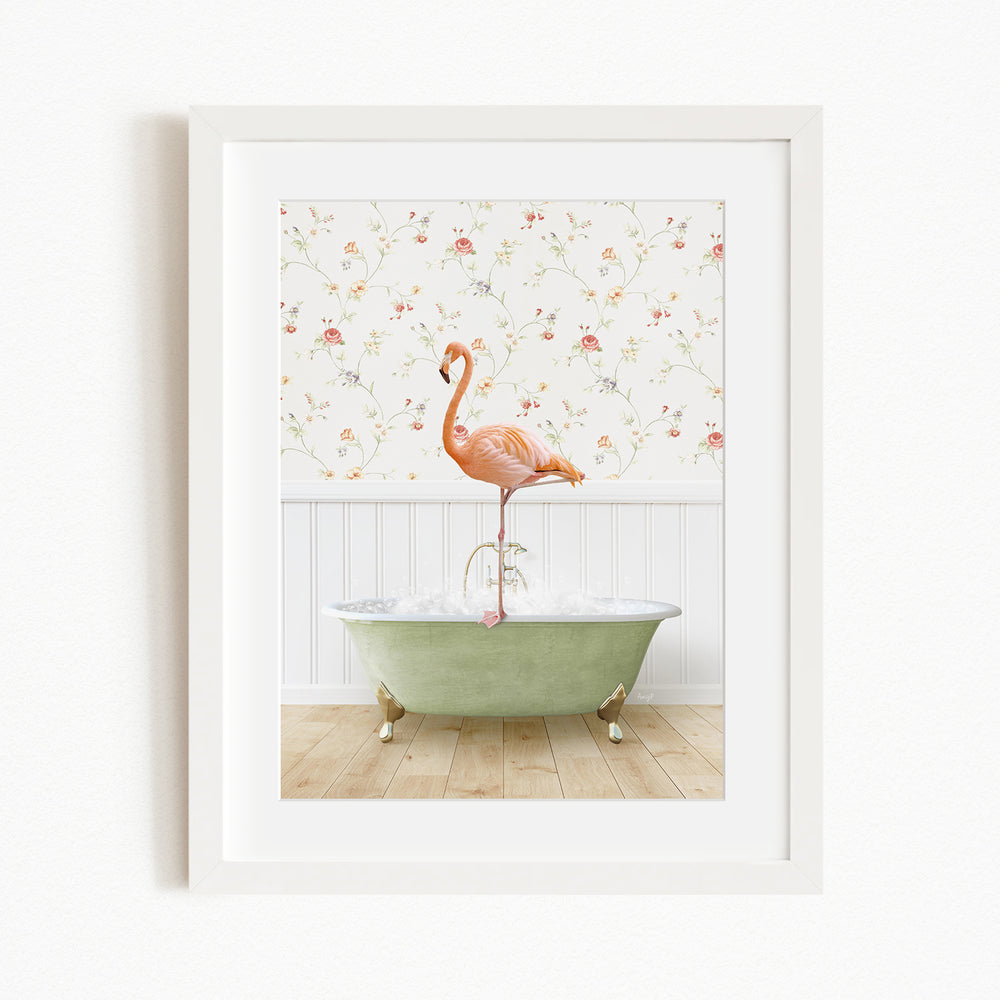 A framed image depicting a pink flamingo standing on the edge of a green bathtub, with a floral wallpaper in the background.