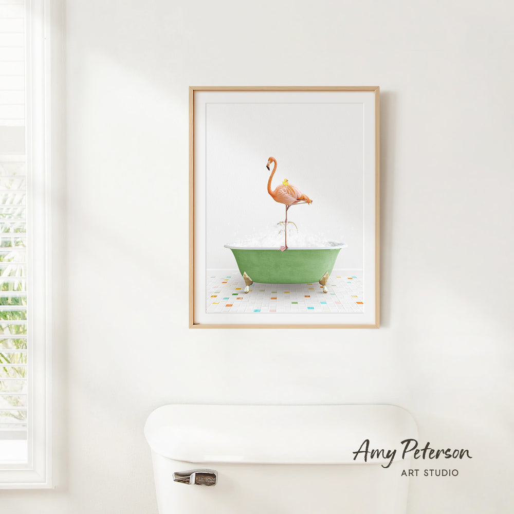 A framed print of a flamingo standing in a green bathtub is hanging on a white wall.