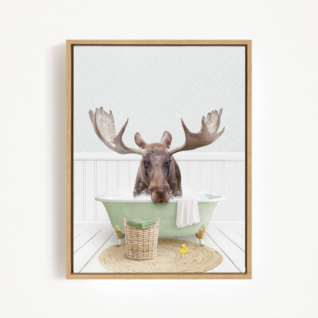 A moose is sitting in a green bathtub filled with water, surrounded by a basket and a rubber duck.