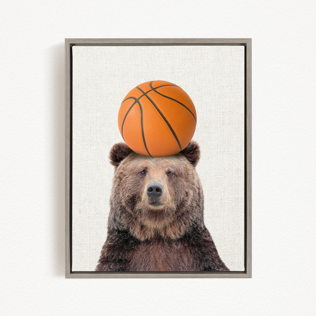 A brown bear balancing a basketball on its head.