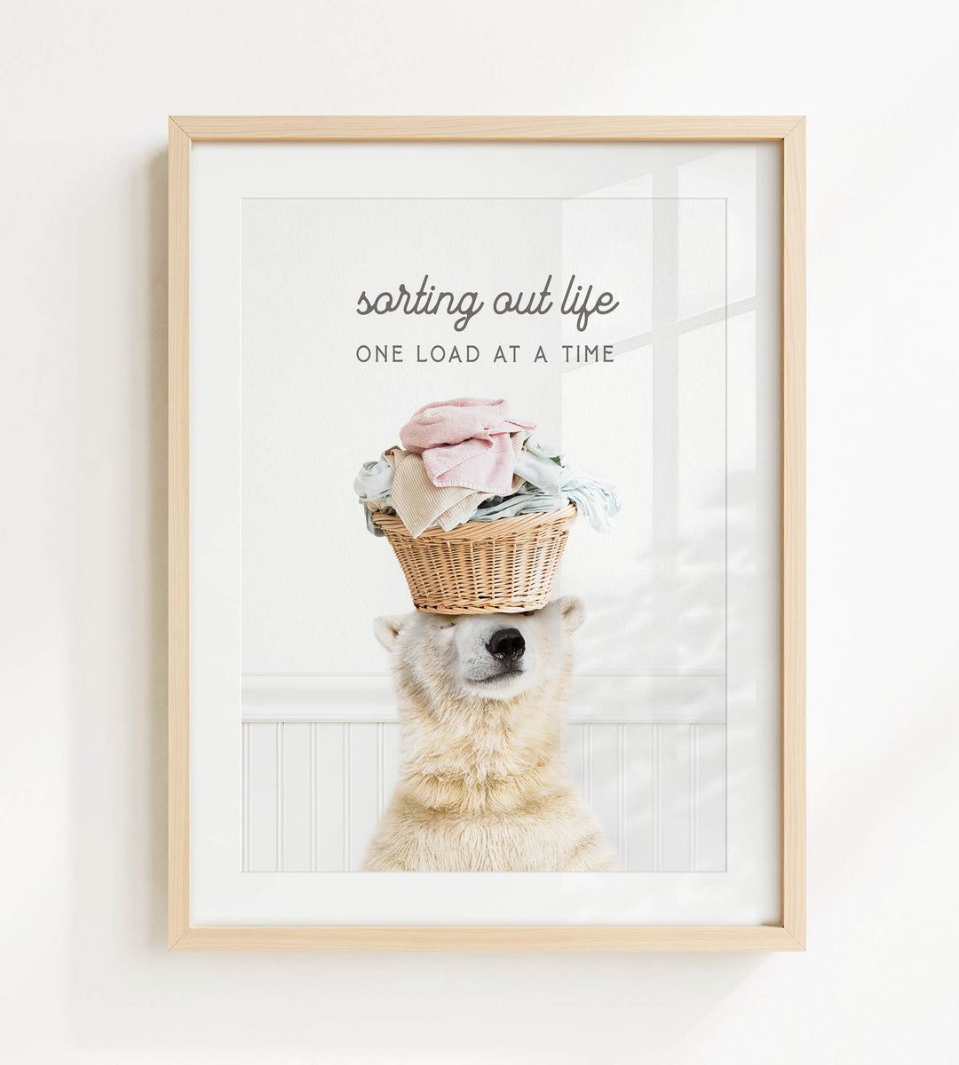 A polar bear balancing a basket of laundry on its head, with the text "sorting out life" and "ONE LOAD AT A TIME" displayed above the image.