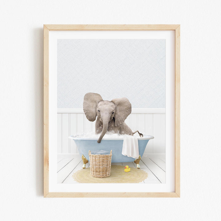 A baby elephant sitting in a blue bathtub filled with water, surrounded by a yellow rubber duck and a basket.