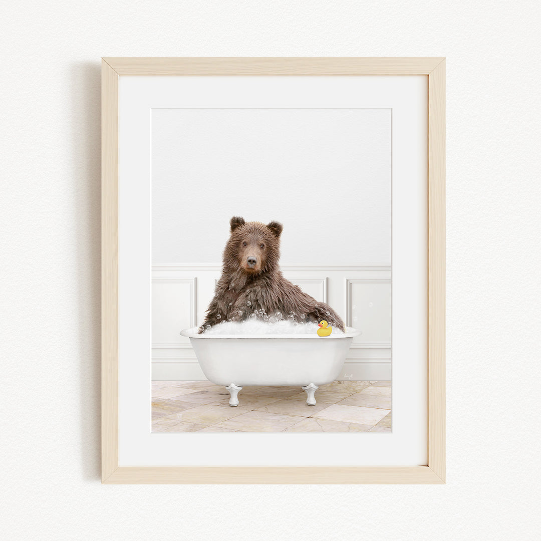 A brown bear sitting in a white bathtub, with a yellow rubber duck floating in the water.