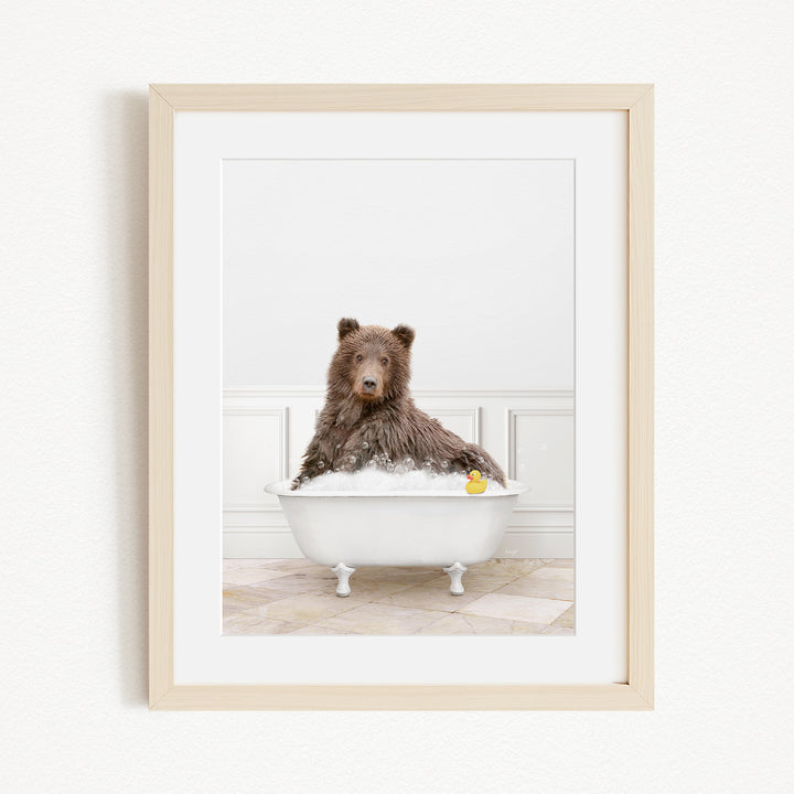 A brown bear sitting in a white bathtub, with a yellow rubber duck floating in the water.