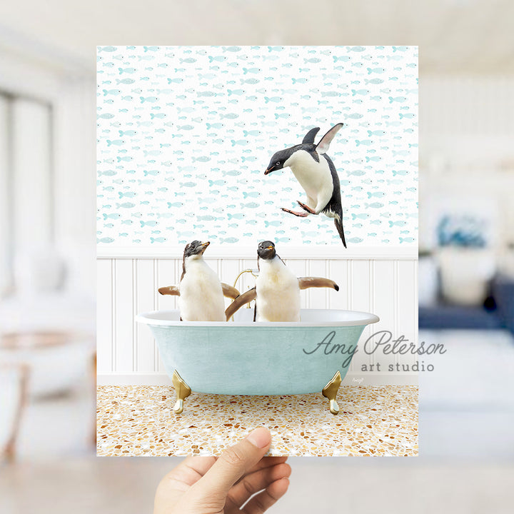 a hand holding a card with three penguins in a bathtub