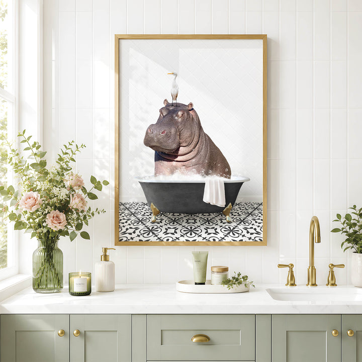 A framed image of a hippopotamus sitting in a bathtub, surrounded by flowers and a decorative vase, is displayed on a wall above a bathroom sink.
