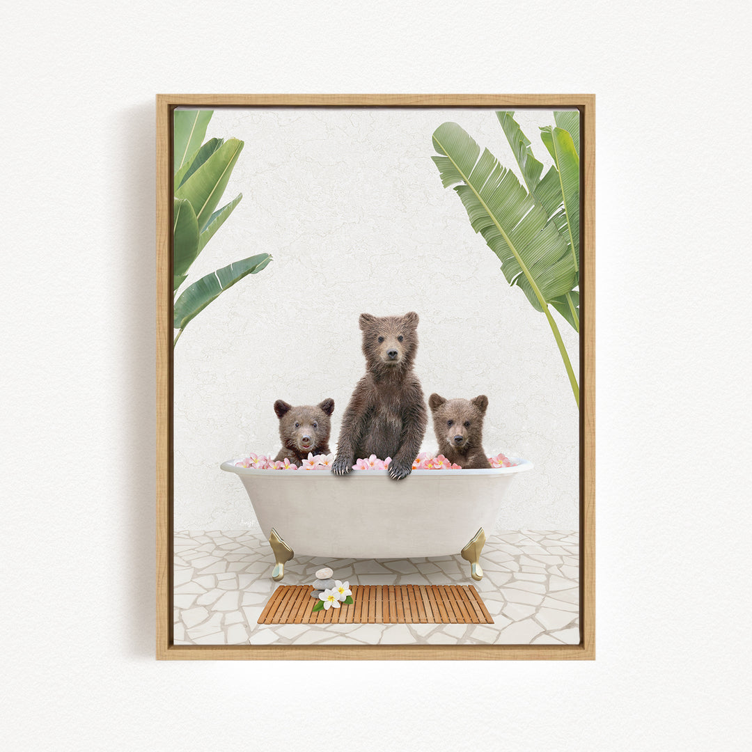Three adorable brown bears sitting in a white bathtub filled with pink flowers, surrounded by green leaves.