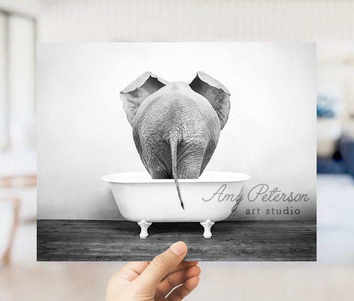 a person holding up a picture of an elephant in a bathtub