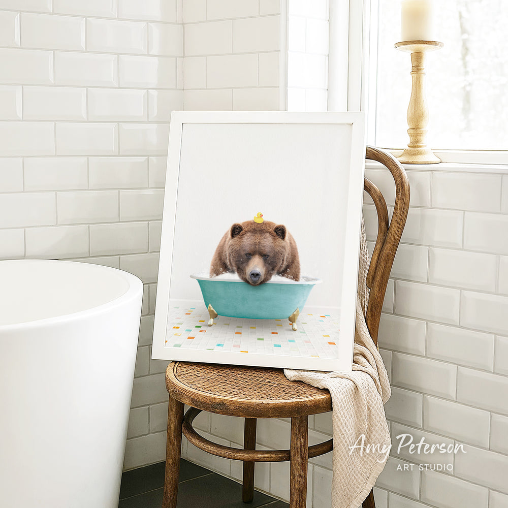 A framed image of a bear sitting in a bathtub, with a yellow rubber duck floating on the water.