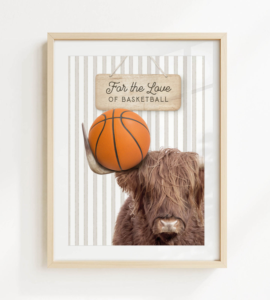 A framed image of a Highland cow holding a basketball, with a sign above it that says "For the Love of Basketball".