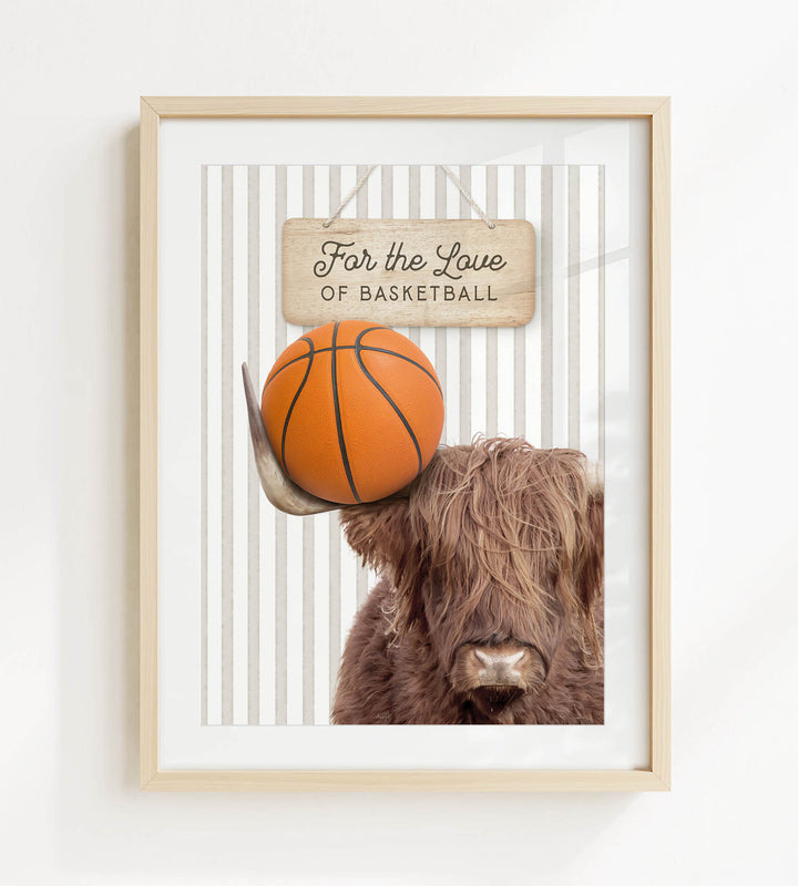 A framed image of a Highland cow holding a basketball, with a sign above it that says "For the Love of Basketball".