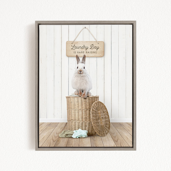A white rabbit sits atop a wicker basket, with a wooden sign above that reads "Laundry Day is Hard Raising".