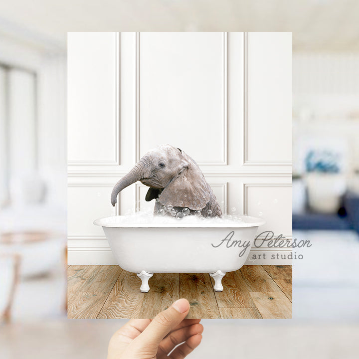 a hand holding a photo of an elephant in a bathtub