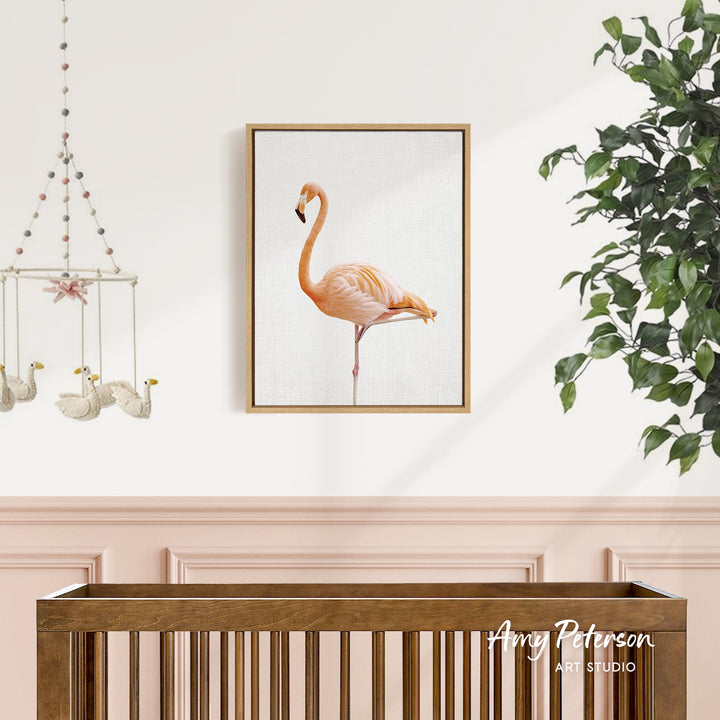 a framed painting of a flamingo on a white wall, with a wooden crib below it.