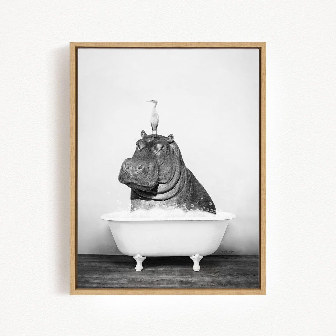A black and white photograph of a hippopotamus sitting in a bathtub, with a bird perched on its head.