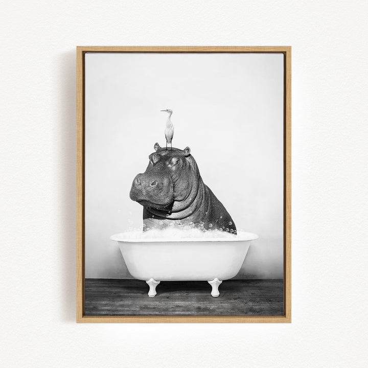 A black and white photograph of a hippopotamus sitting in a bathtub, with a bird perched on its head.